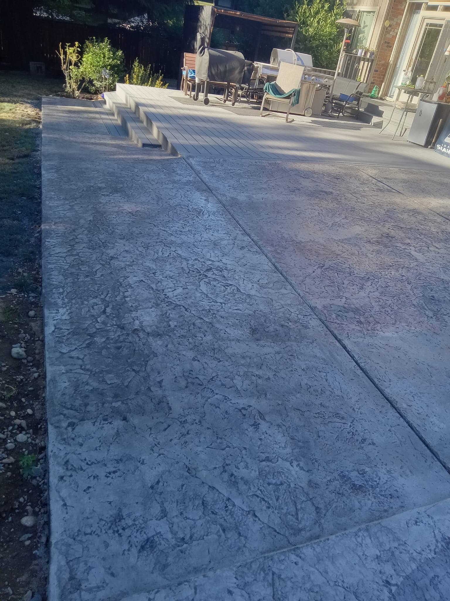 Wide stamped concrete patio with steps and outdoor living area